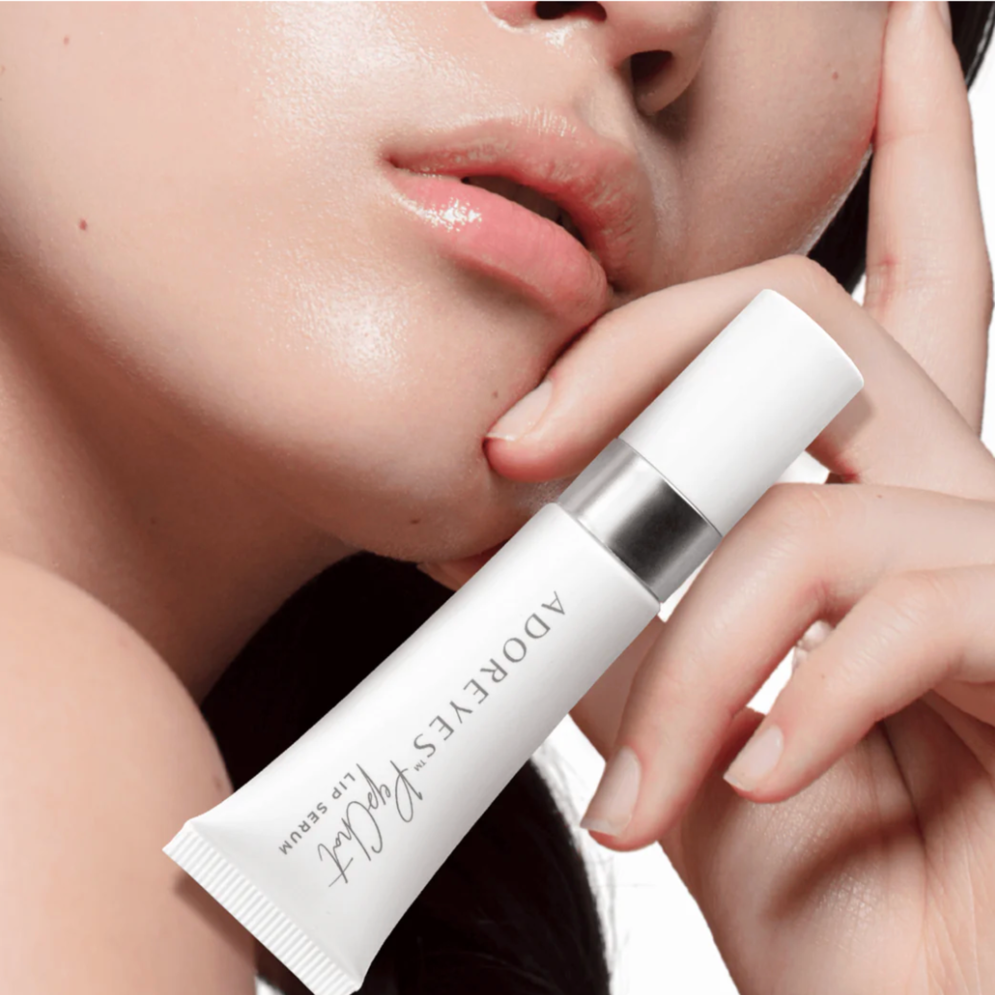 Close-up of a person holding a skincare product labeled 'Adore Eyes' with a blurred background.