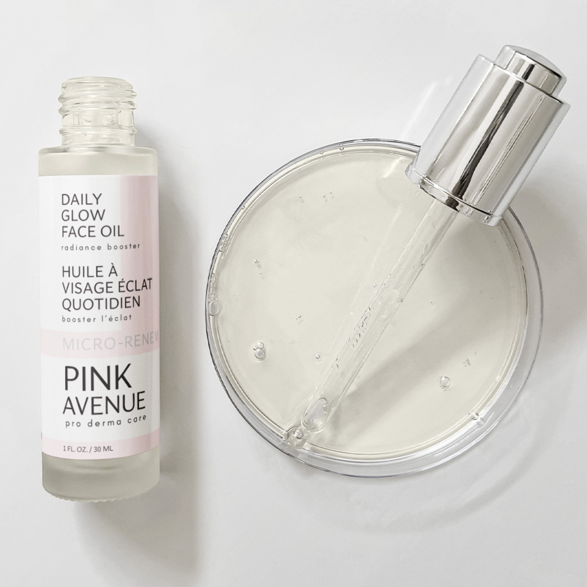 Pink Avenue Daily Glow Face Oil bottle and a clear container with a dropper on a white background