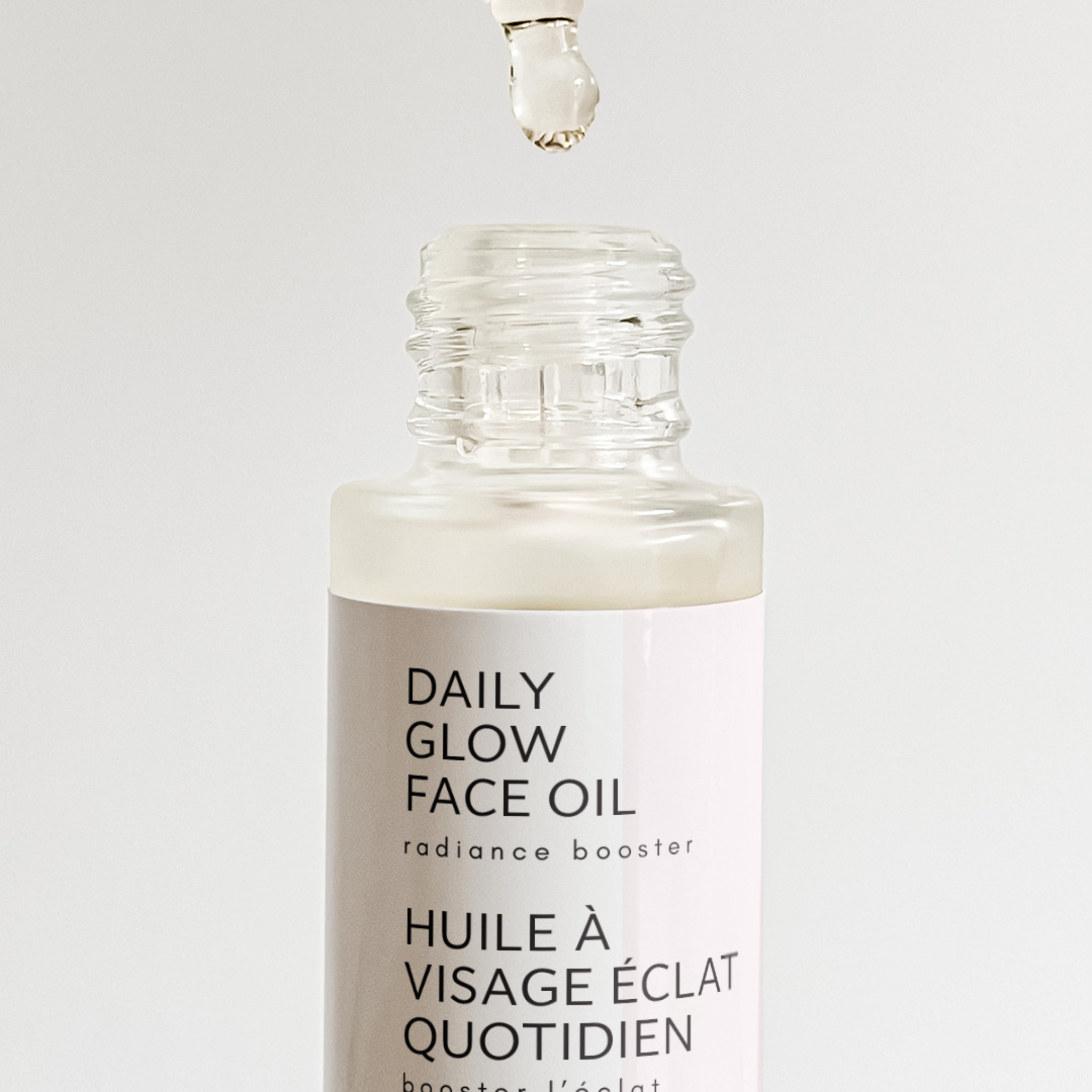 Bottle of Daily Glow Face Oil with dropper on a white background