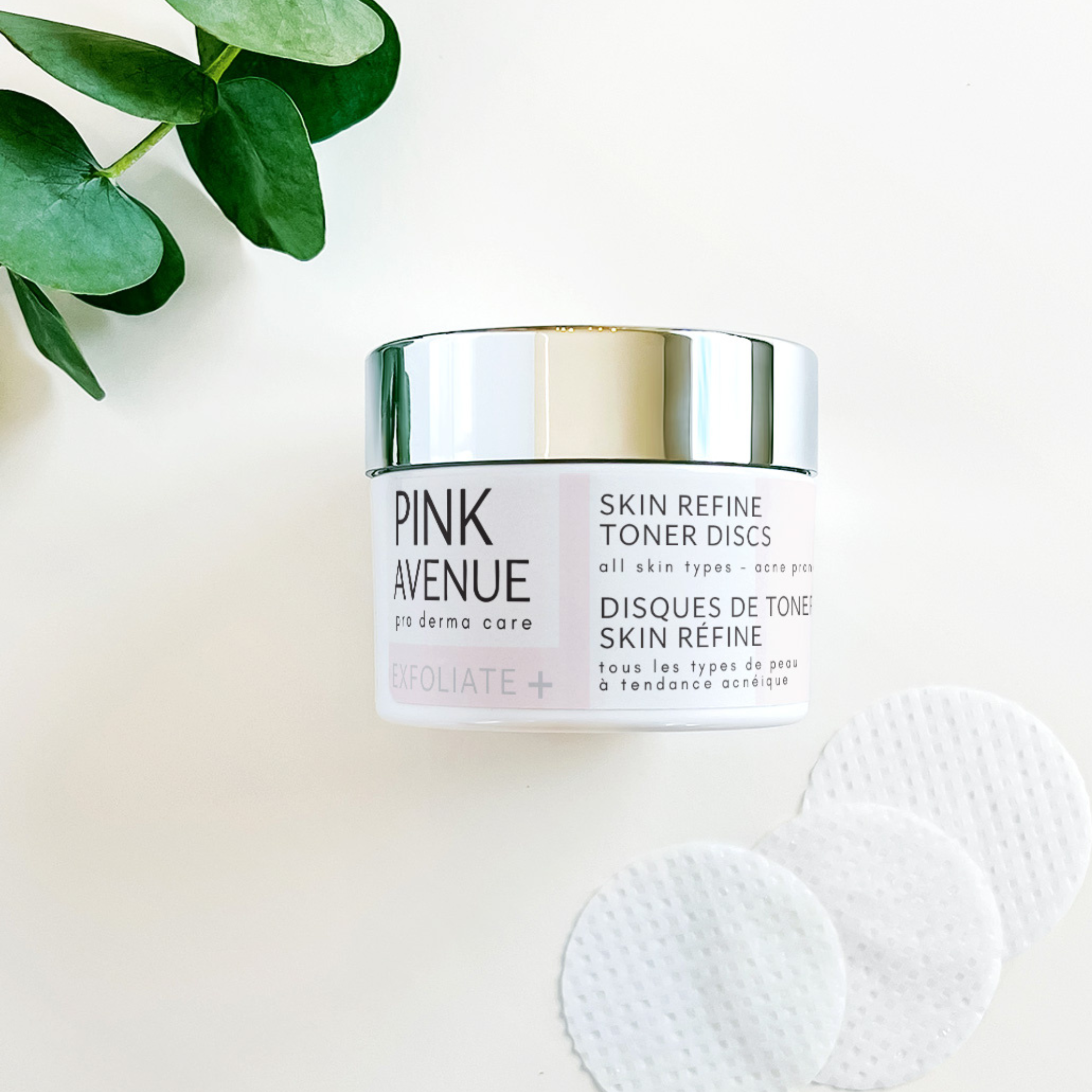 Pink Avenue skincare product on a white background with green leaves
