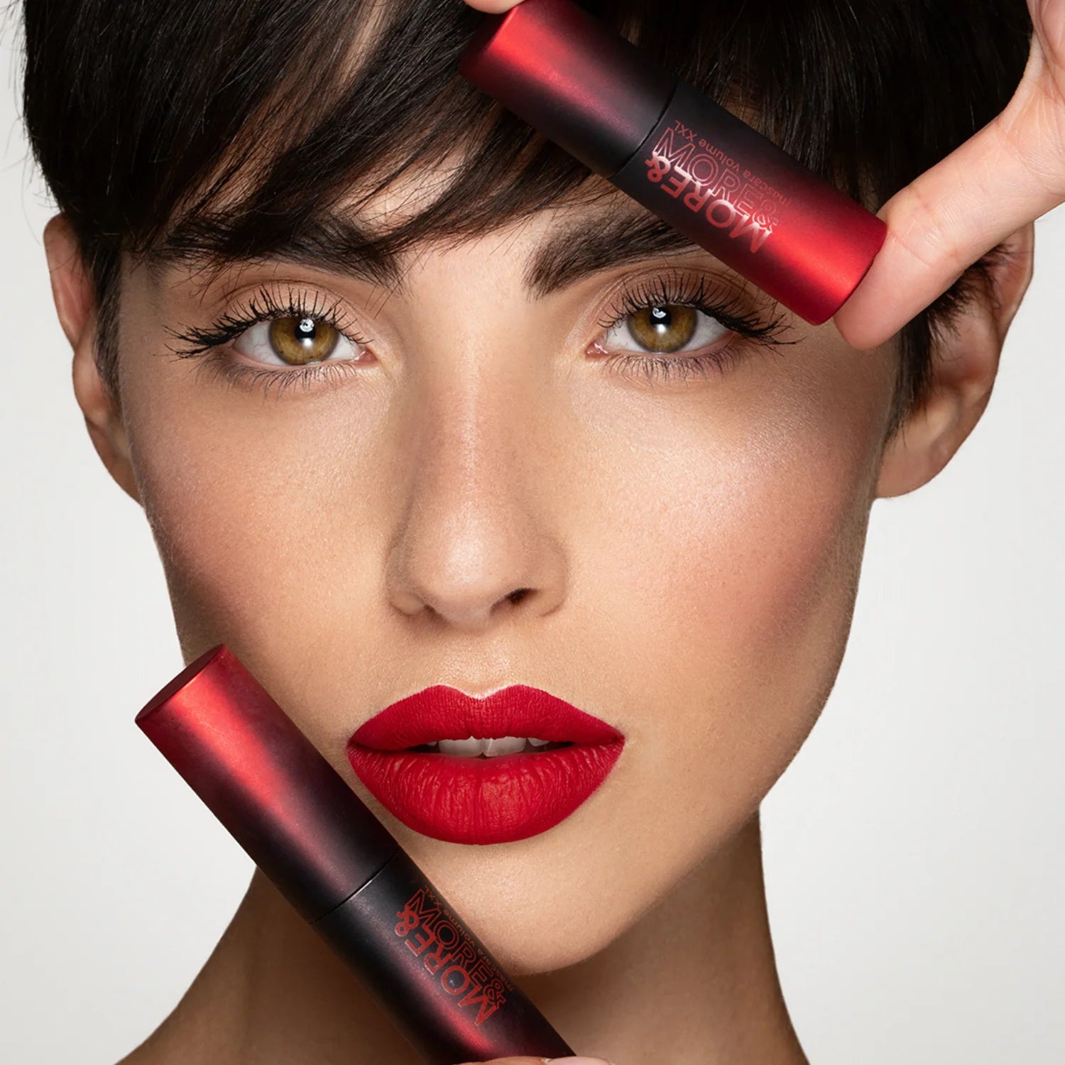 Femme avec un rouge à lèvres rouge tenant un tube de rouge à lèvres rouge sur fond neutre