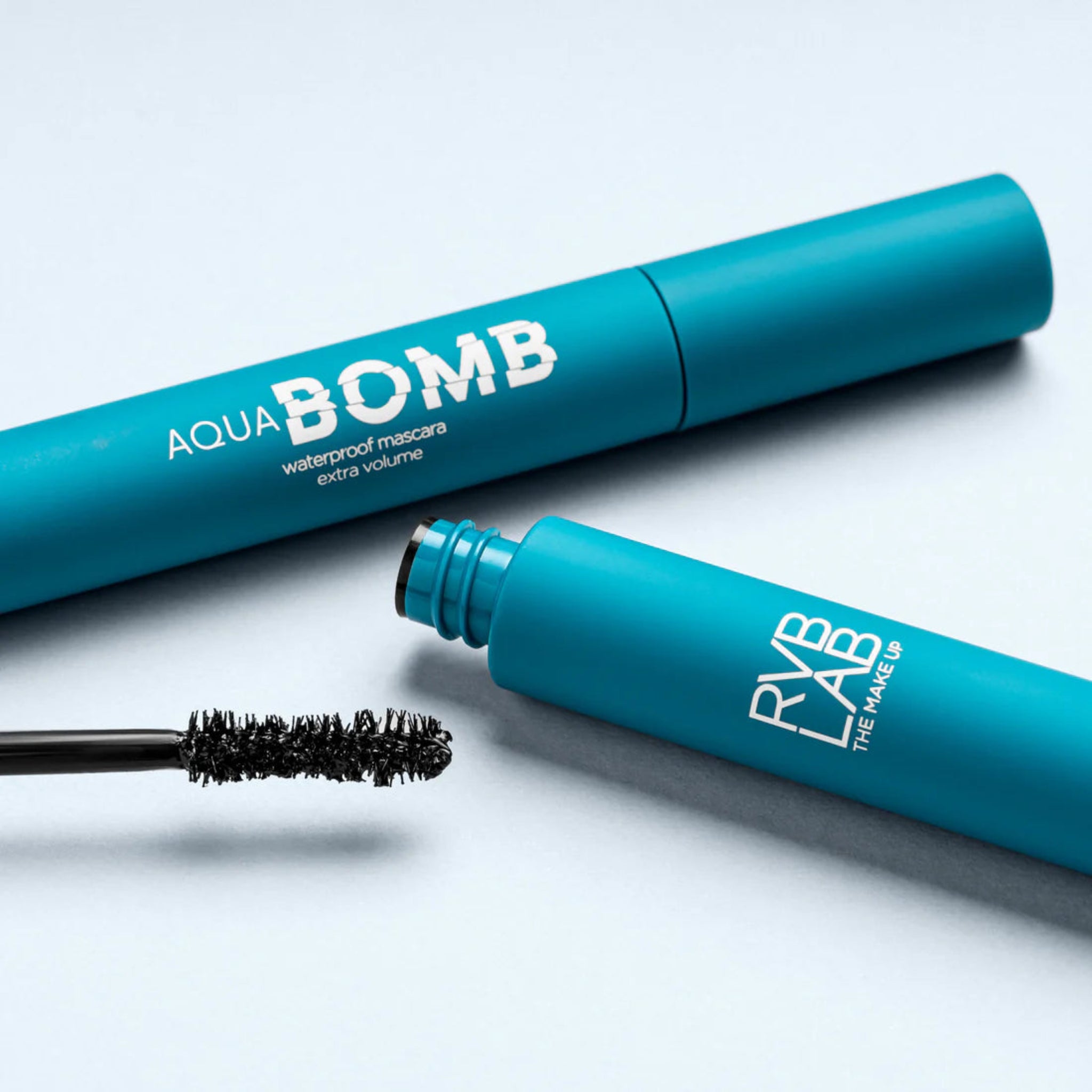 Blue mascara with 'Aqua Bomb' and 'RVB The Makeup' branding on a light gray background