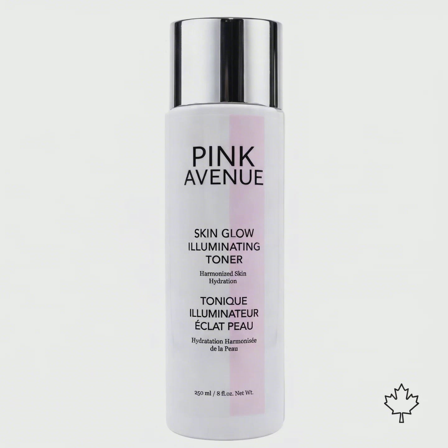 A premium skincare product shot featuring a Pink Avenue Skin Glow Illuminating Toner bottle (white glossy bottle with silver cap) positioned center frame against a clean white background. A transparent_ very light gold liquid splashes dynam